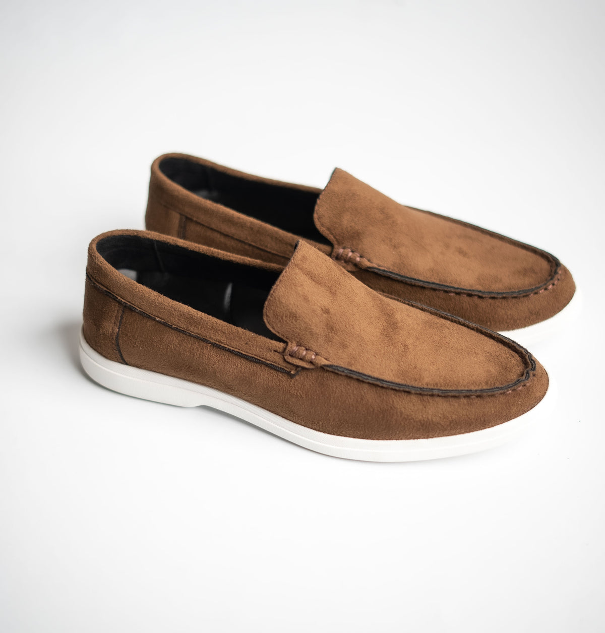 Pair of brown suede loafers on a white background