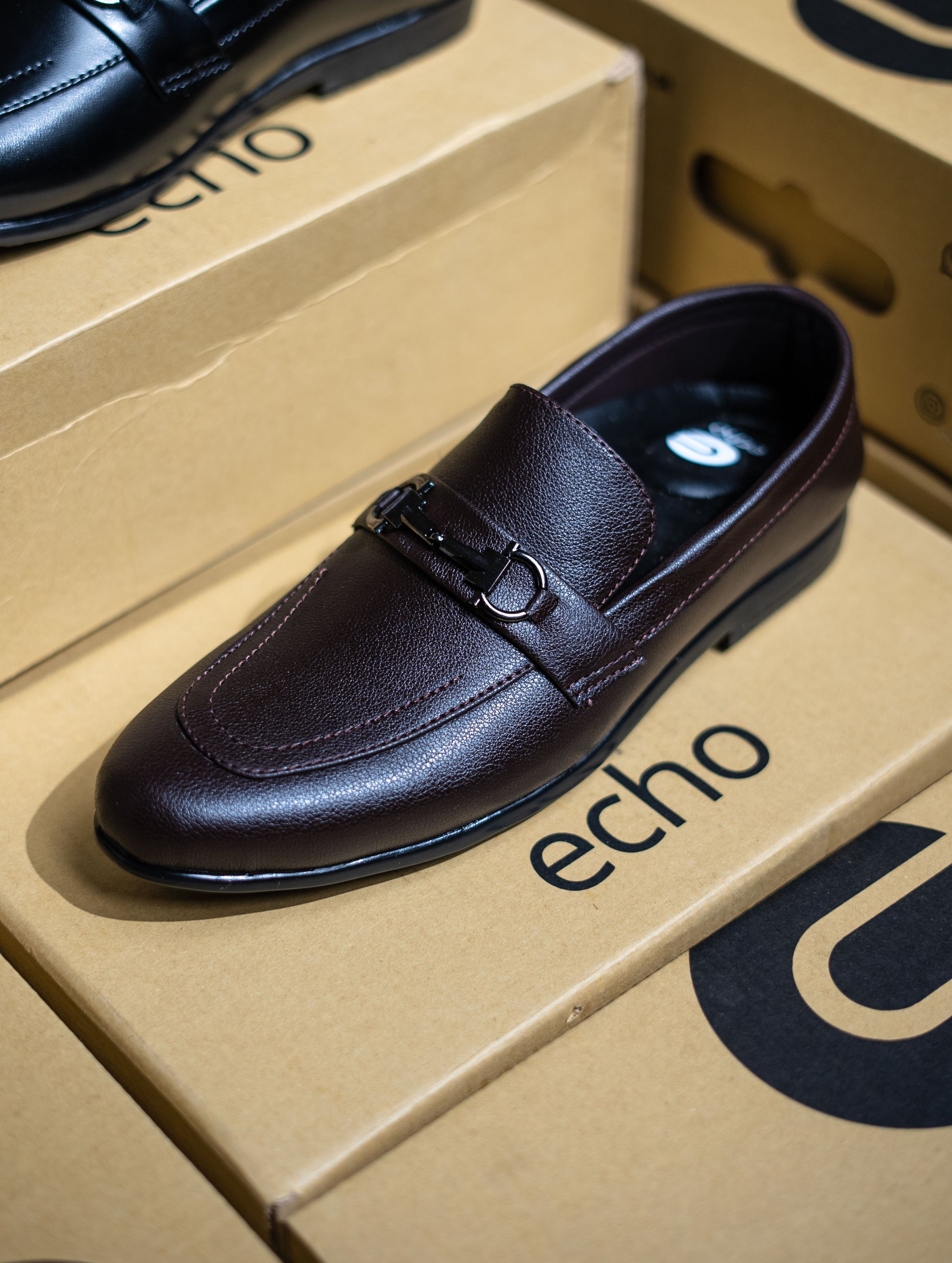 Black leather shoe on an 'echo' branded box