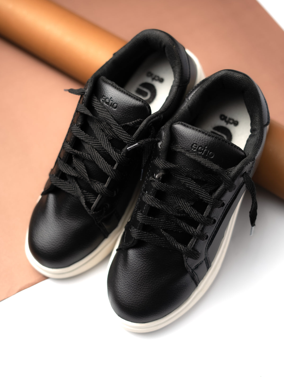Black sneakers with white soles on a light background