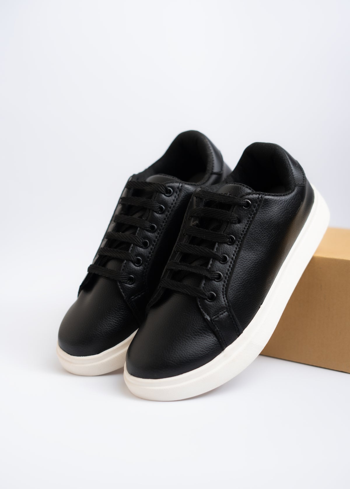 Black sneakers with white soles on a light gray background