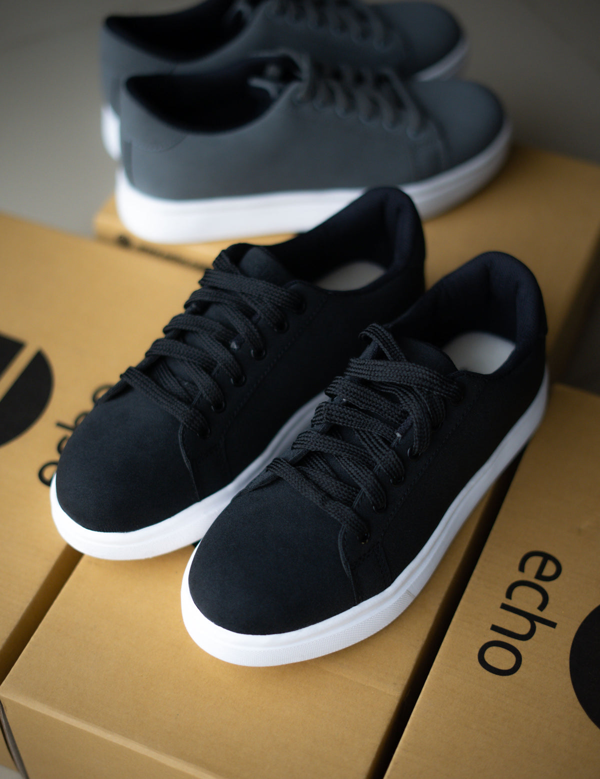 Black sneakers on an 'echo' branded box with a gray background