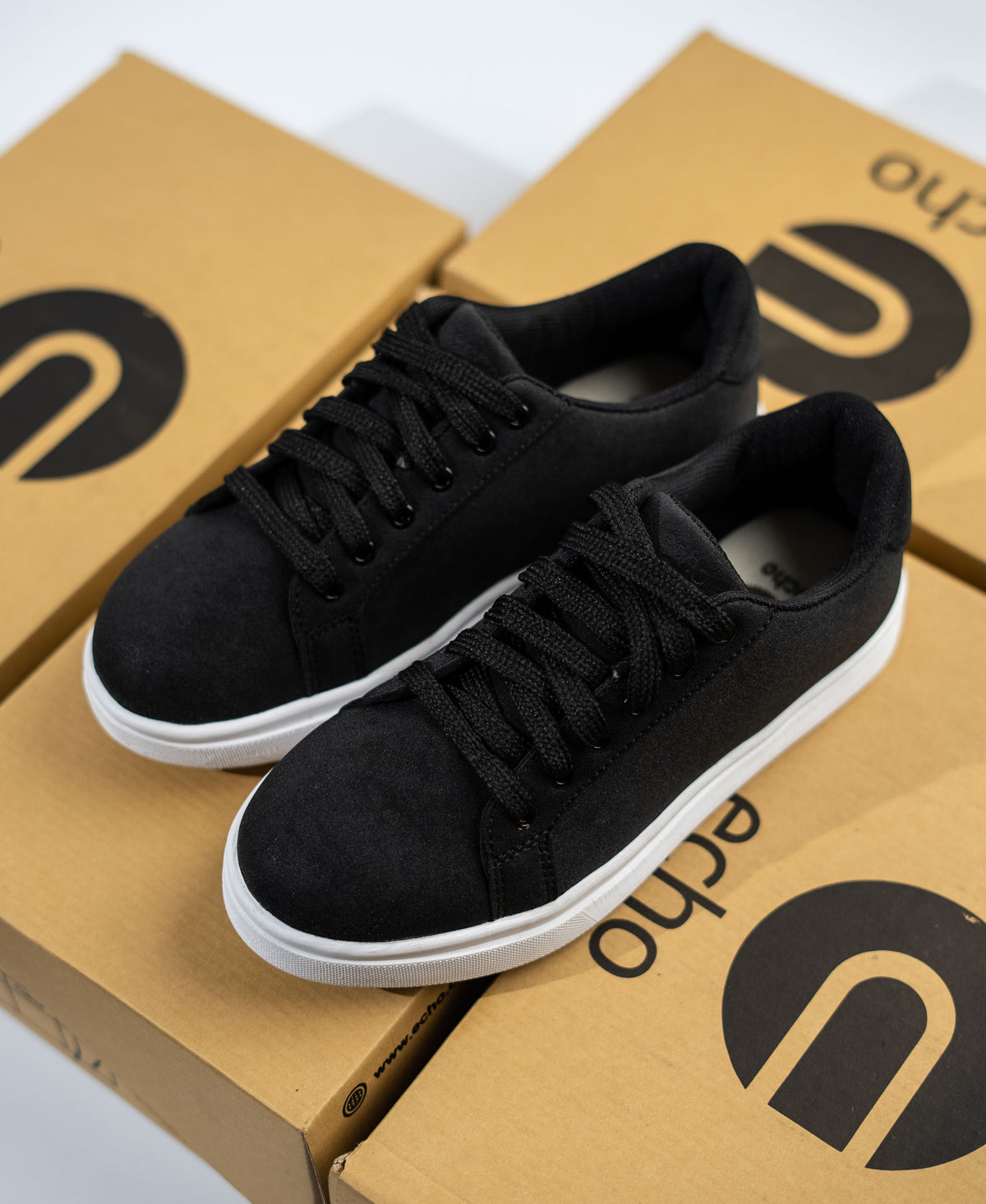 Black sneakers on a cardboard box with 'echo' branding.