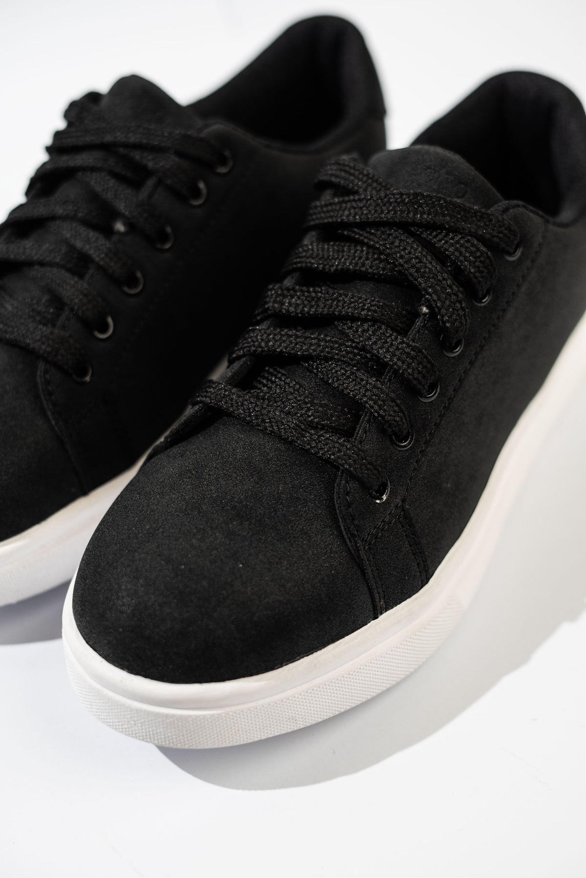 Black sneakers with white soles on a light gray background