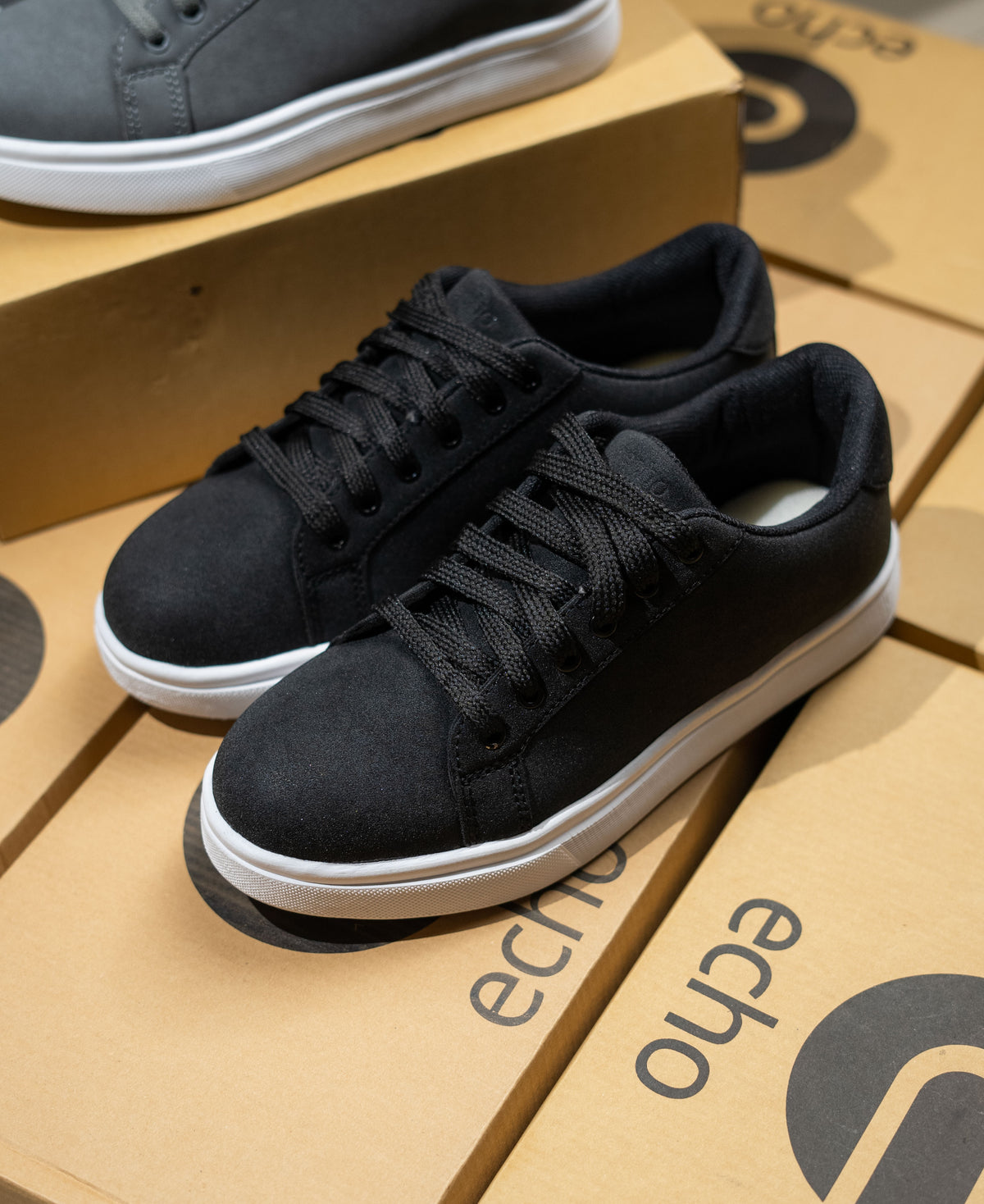 Black sneakers on a cardboard box with 'echo' branding