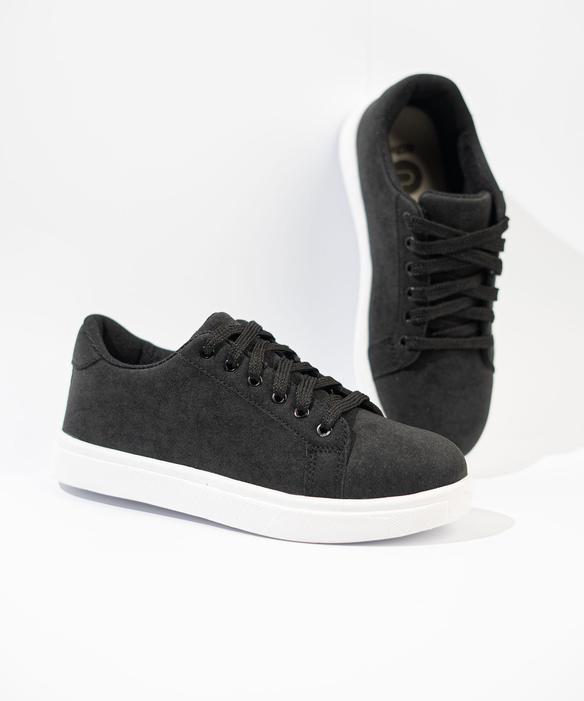 Black sneakers with white soles on a light gray background