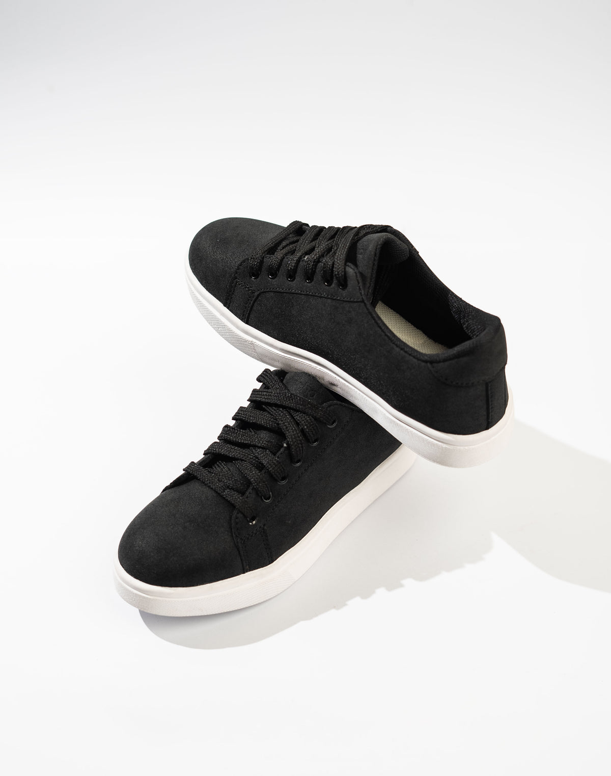 Black sneakers with white soles on a white background