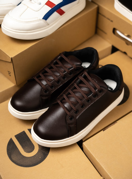 Brown sneakers on a cardboard box with a white sneaker in the background