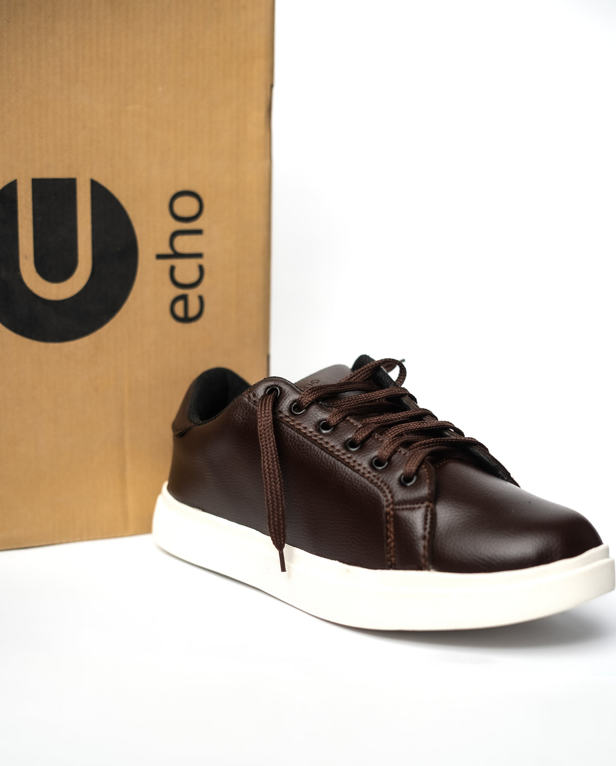 Brown sneaker with white sole in front of an 'echo' branded box on a white background