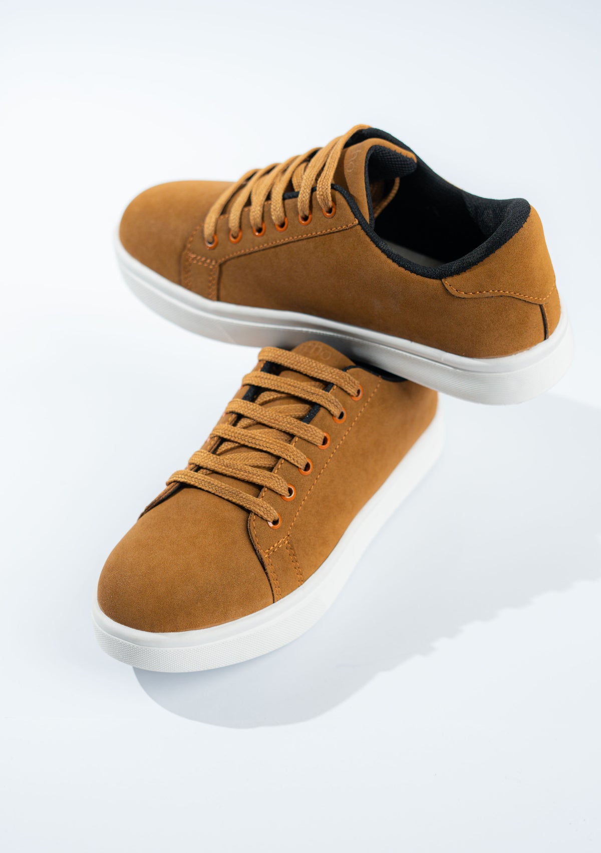 Brown sneakers with white soles on a light gray background