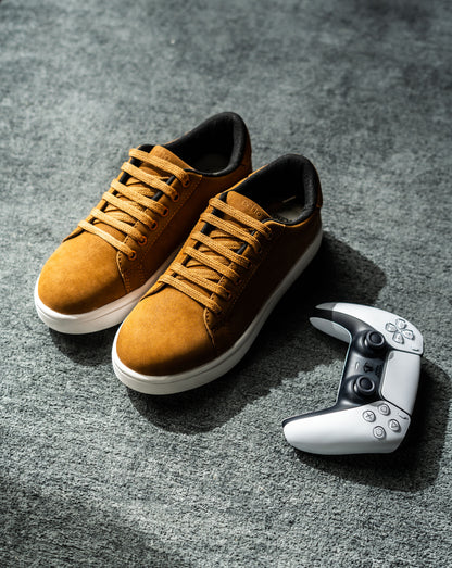 Pair of brown sneakers on a gray surface with a gaming controller next to them.