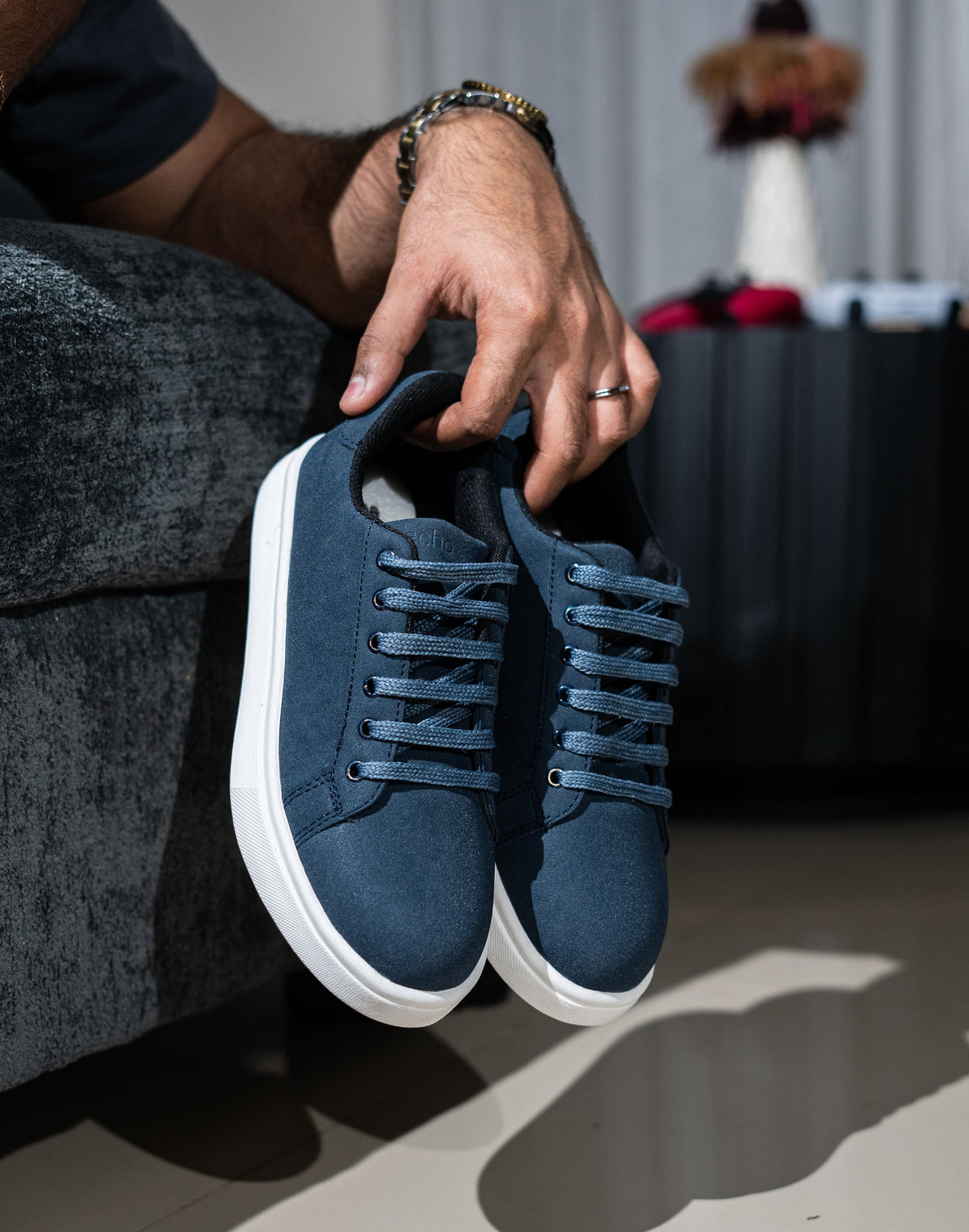 Person holding a pair of blue sneakers with white soles.