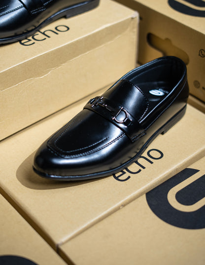 Black leather loafer shoe on a cardboard box with 'echo' branding.