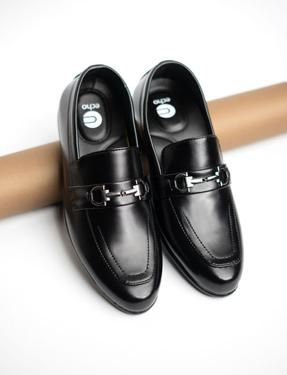 Pair of black loafers with metallic buckles on a white background