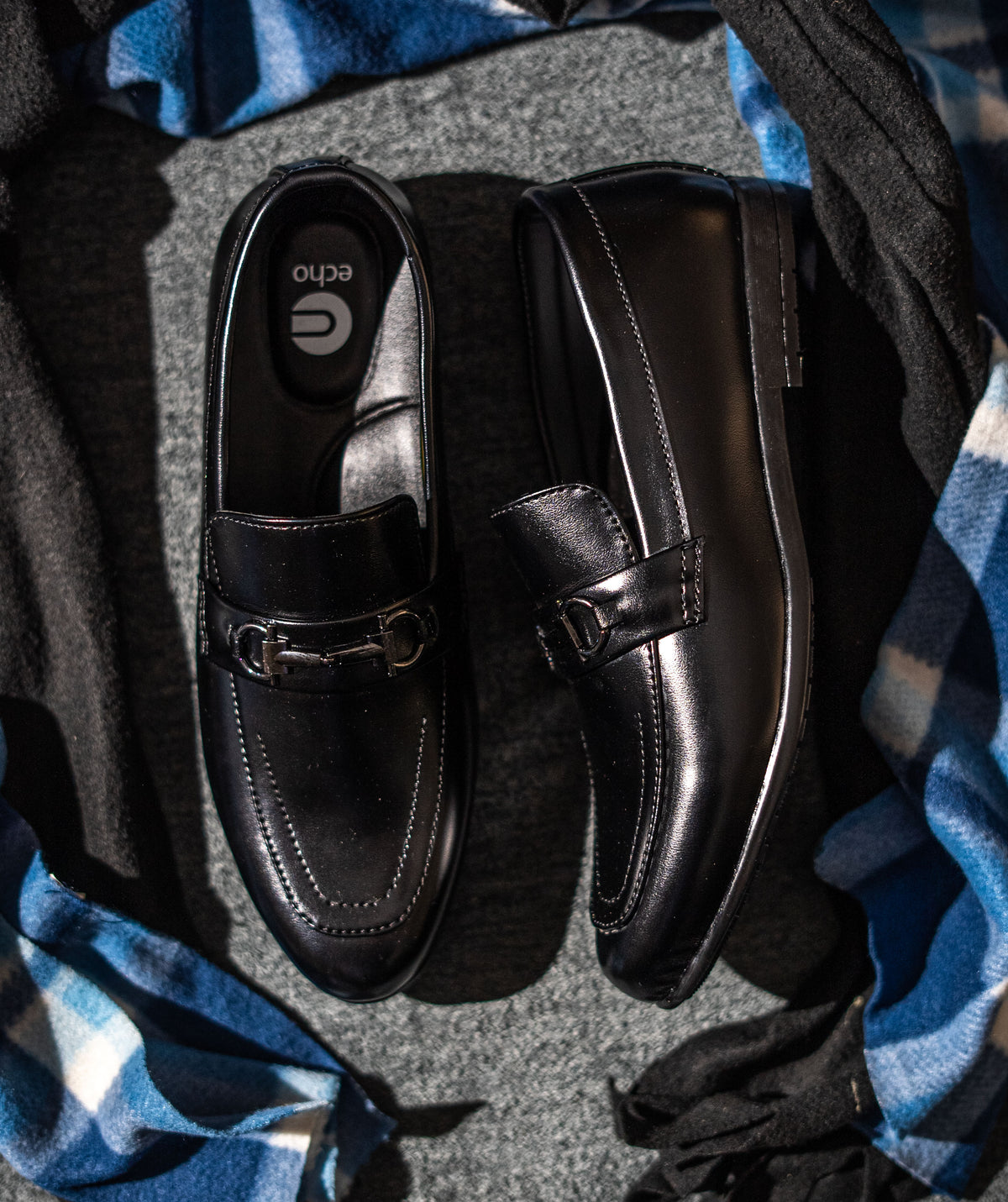 Black loafers on a textured surface with blue fabric