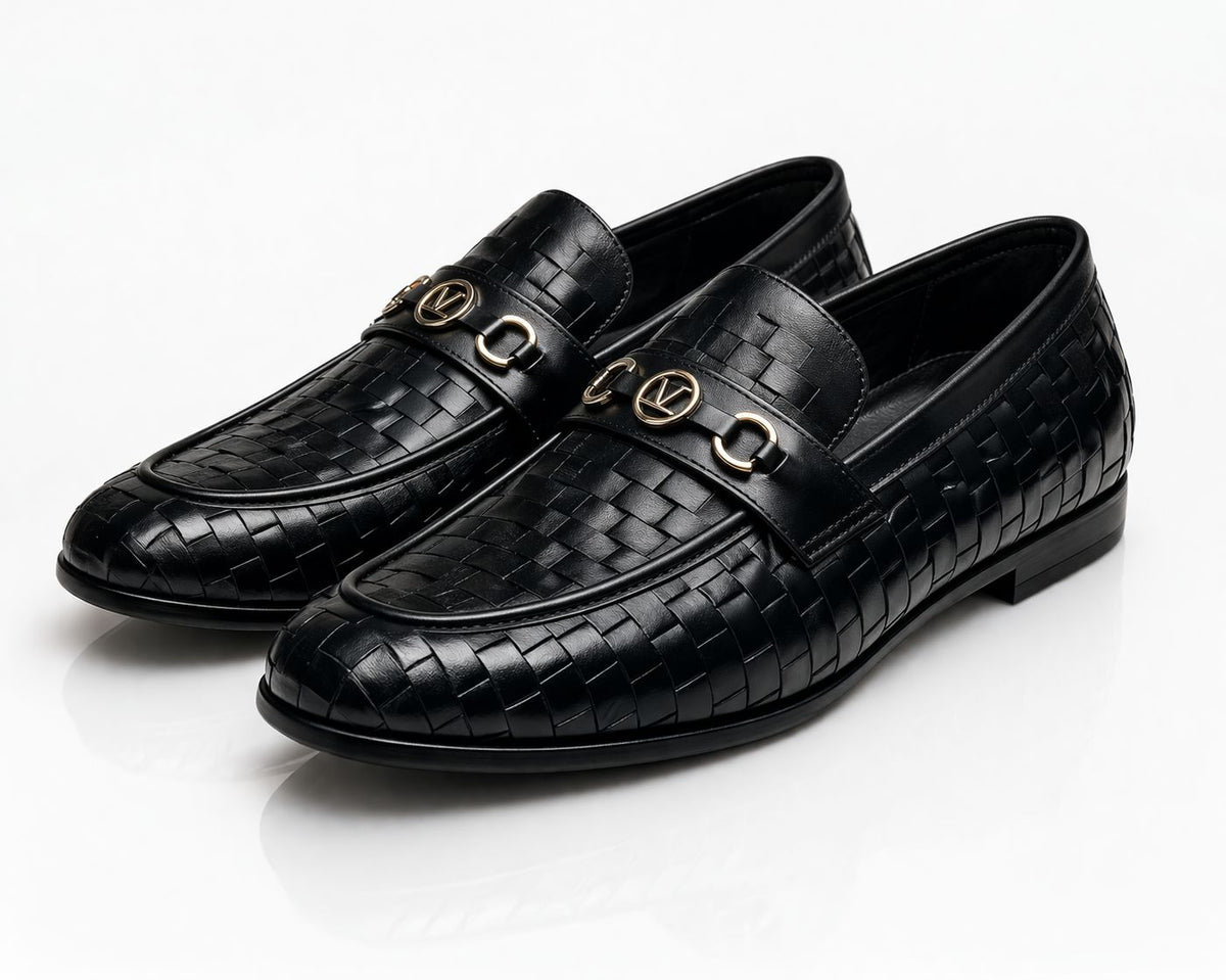 Pair of black woven loafers with gold buckles on a white background