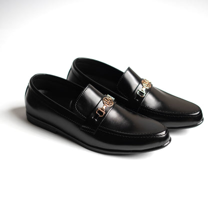 Pair of black leather loafers with gold buckles on a white background