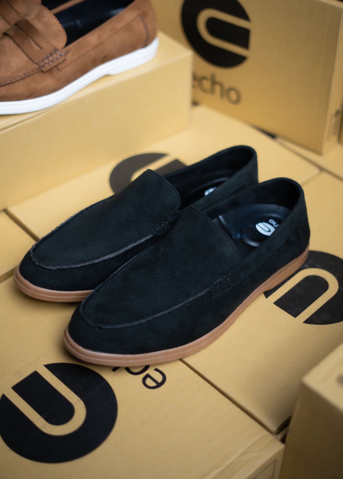 Black loafers on a cardboard box with 'ECHO' branding