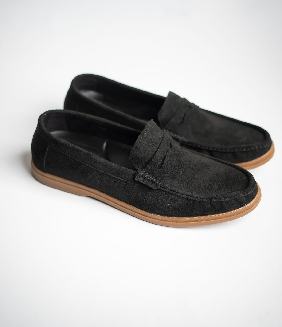 Black loafers with brown soles on a white background
