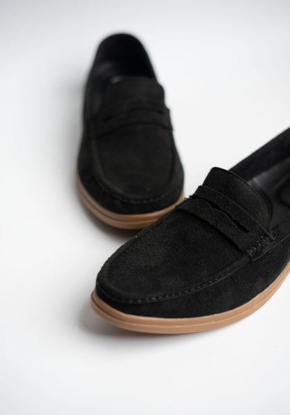 Black loafers with brown soles on a white background