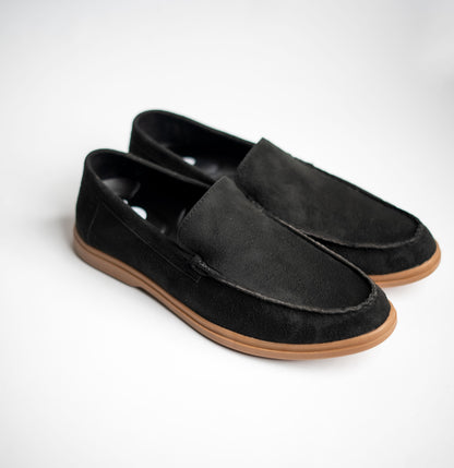 Pair of black loafers with brown soles on a white background