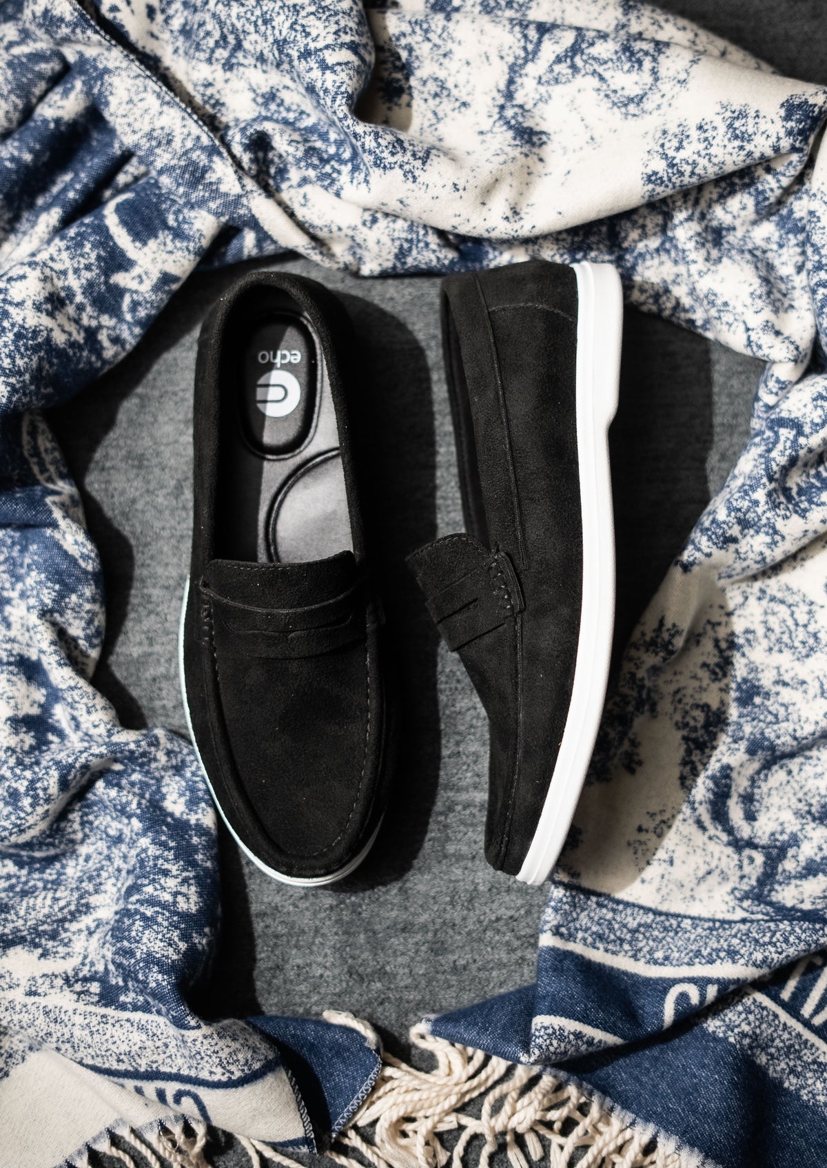 Black slip-on shoes on a textured fabric background