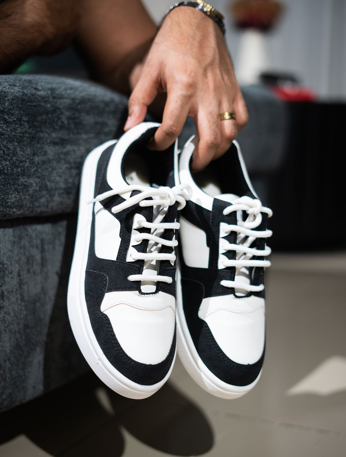 Black and white sneakers held by a person with a blurred background