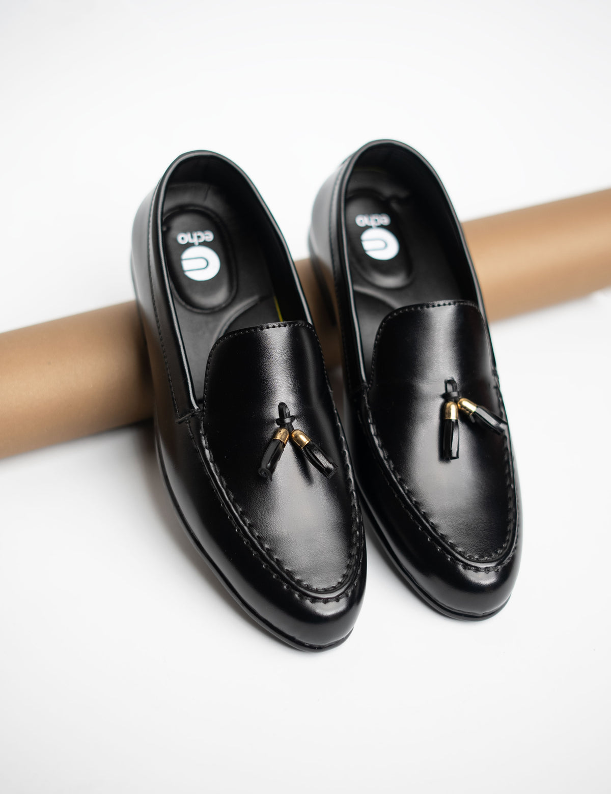 Pair of black loafers with tassels on a white background