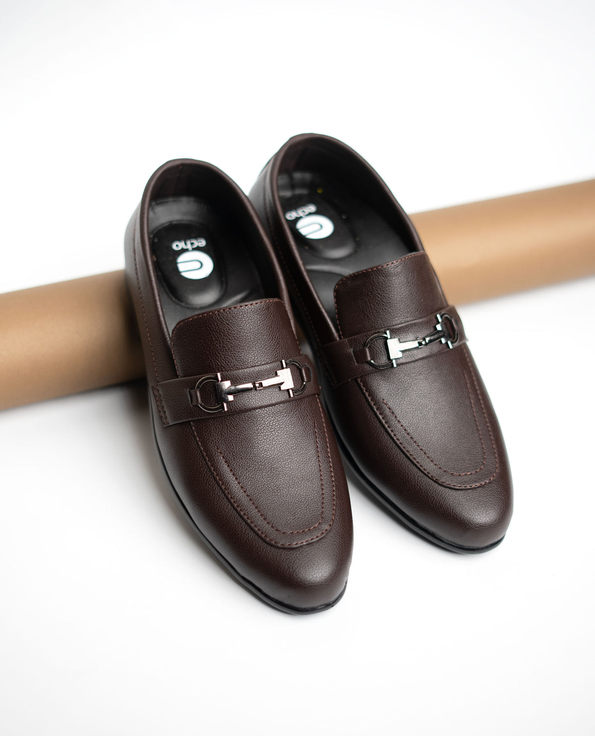 Pair of brown leather loafers with a metal buckle on a white background