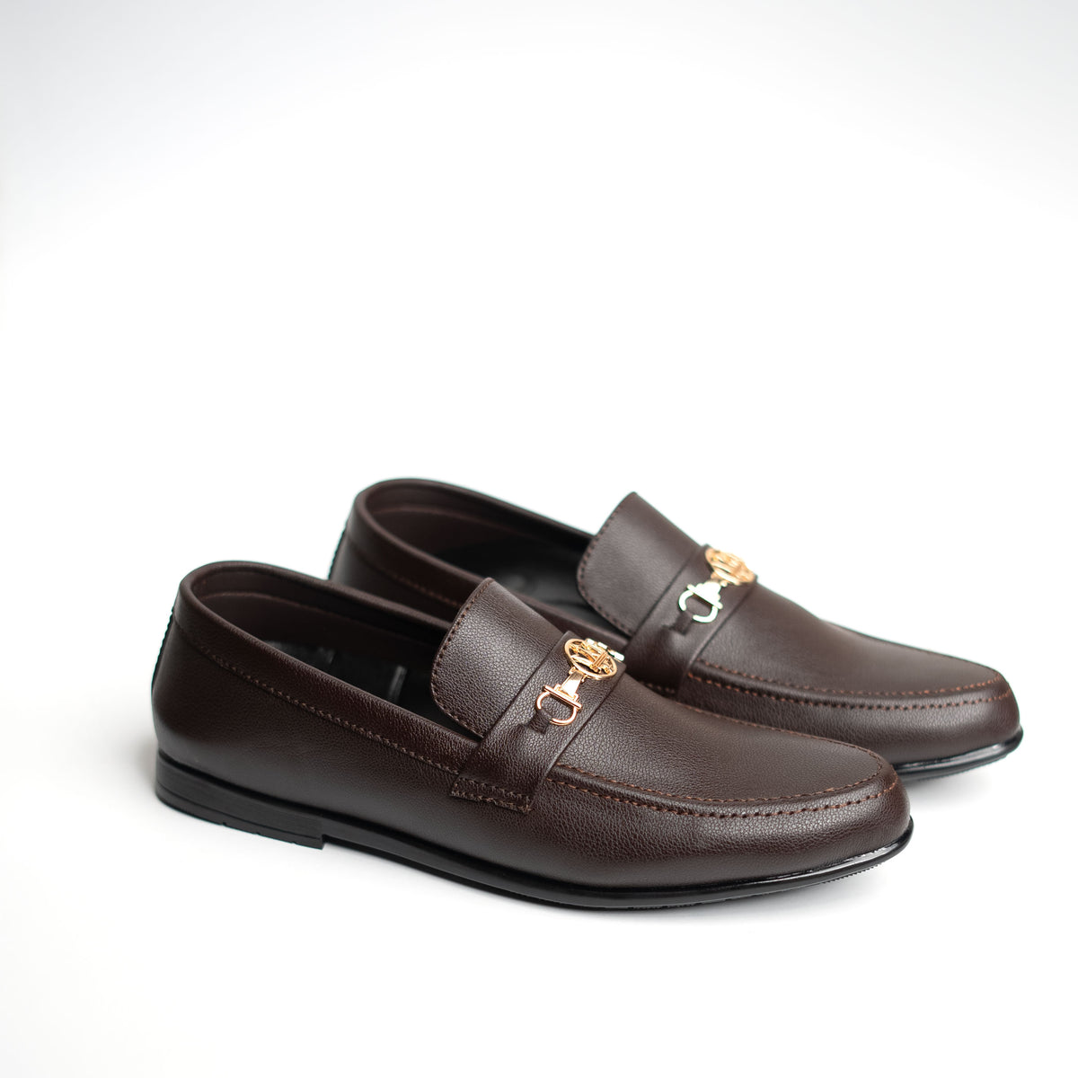 Pair of brown loafers with gold accents on a white background