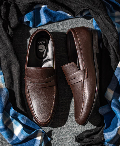 Pair of brown loafers on a textured surface with blue fabric underneath