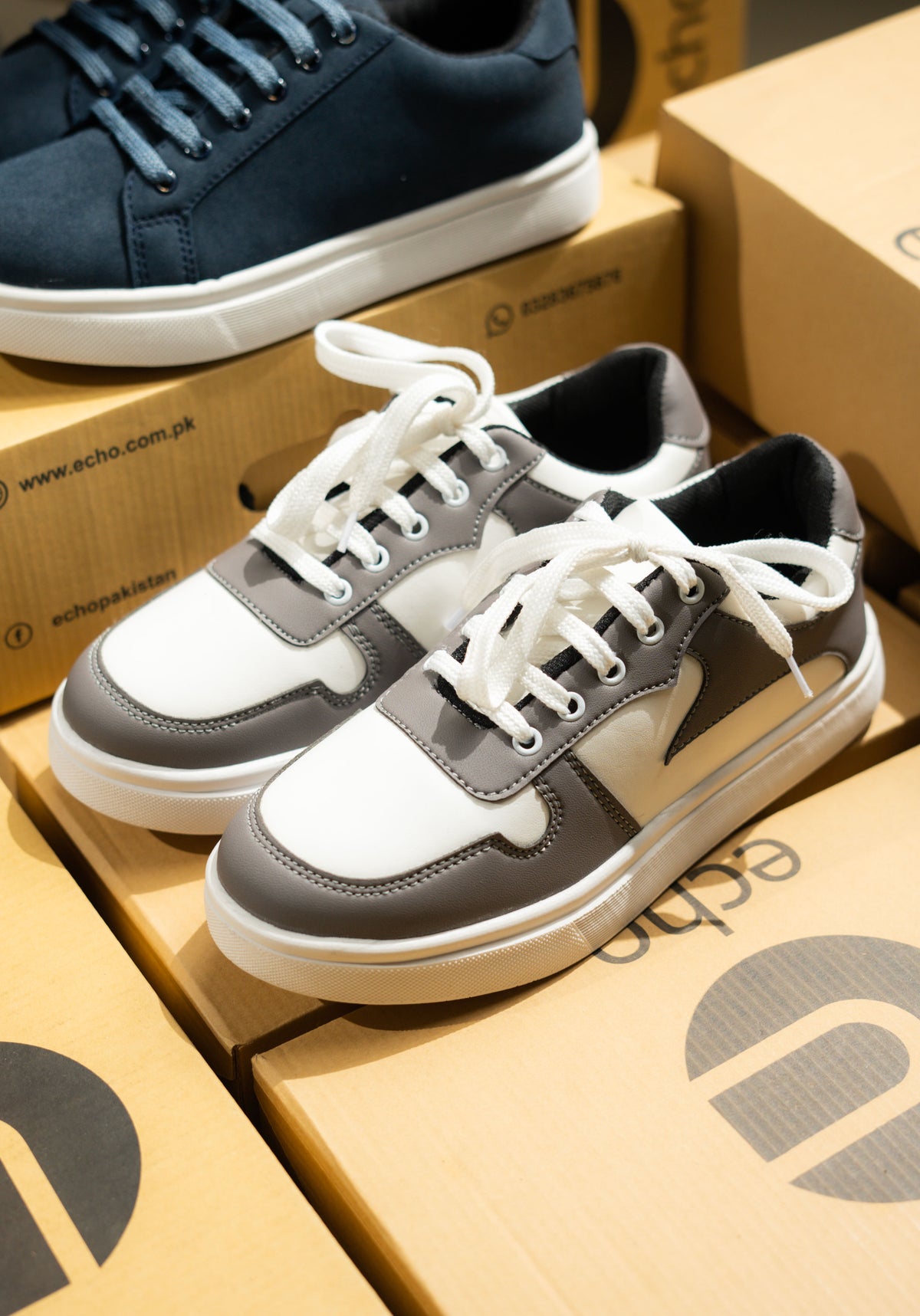 Pair of gray and white sneakers on a cardboard box with 'Echo' branding.