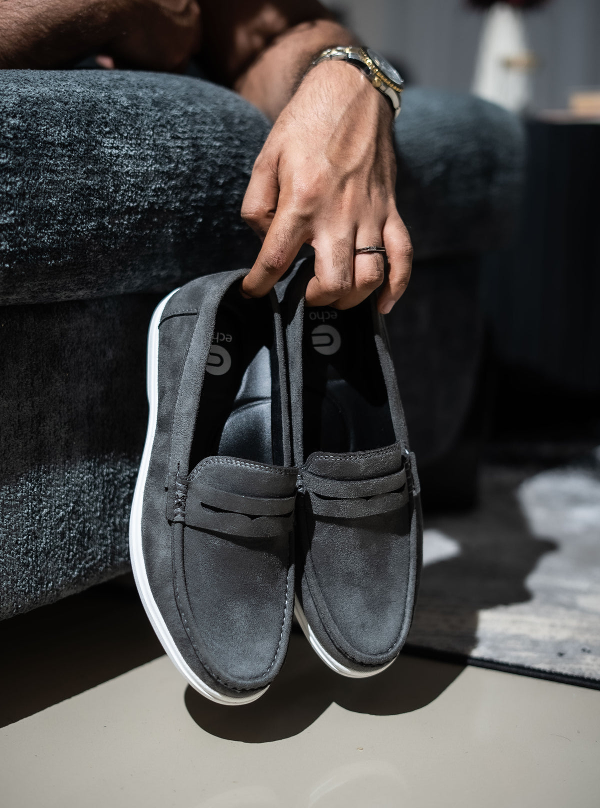 Person holding a pair of gray slip-on shoes with white soles.