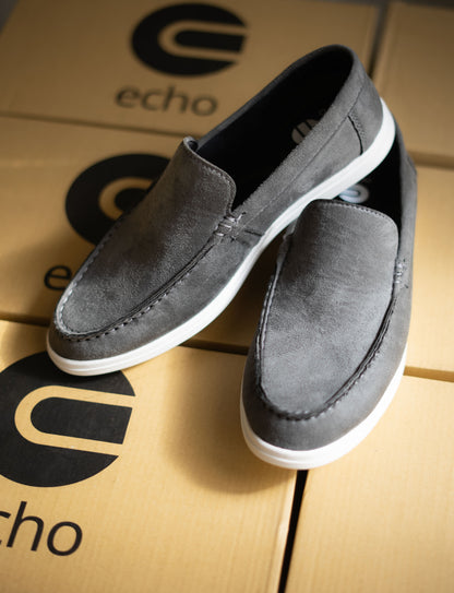 Gray loafers on a cardboard surface with 'echo' branding.