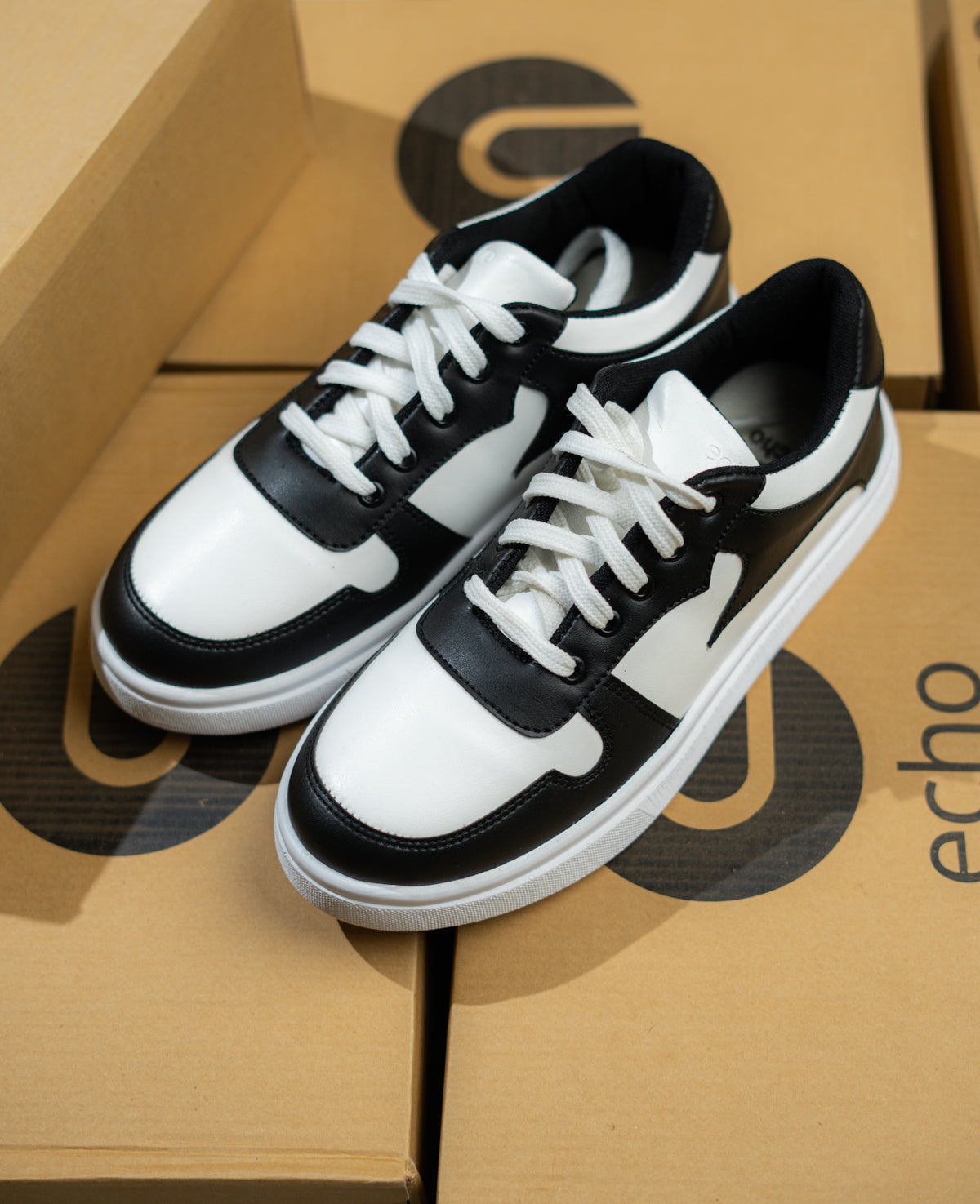 Black and white sneakers on a cardboard box with 'echo' branding.