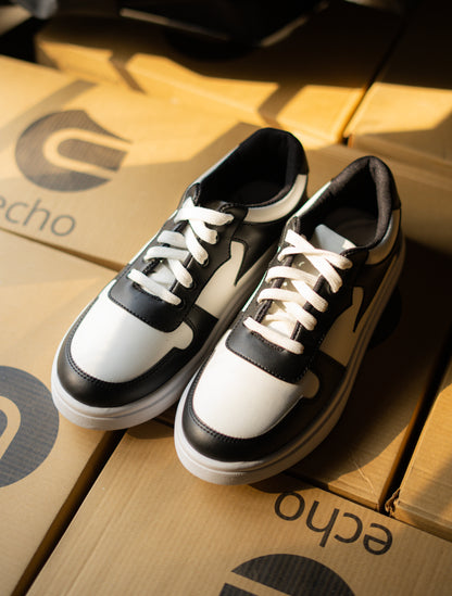Black and white sneakers on a cardboard surface with 'echo' branding.