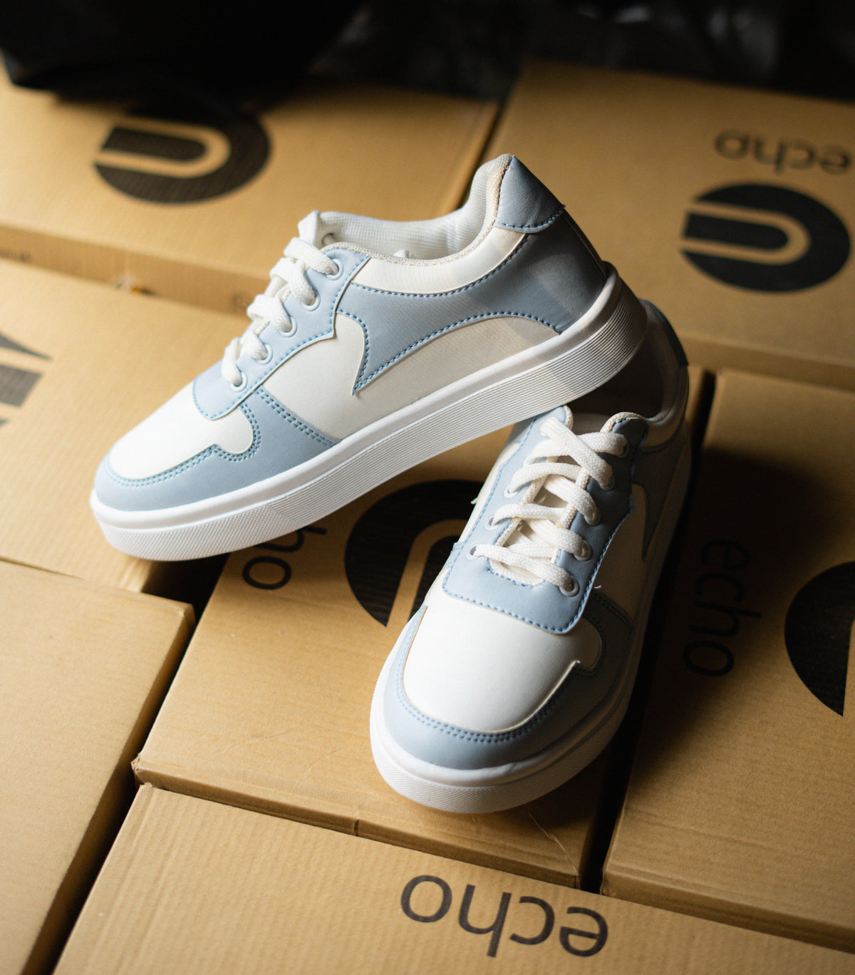 Pair of light blue and white sneakers on cardboard boxes with 'echo' branding.