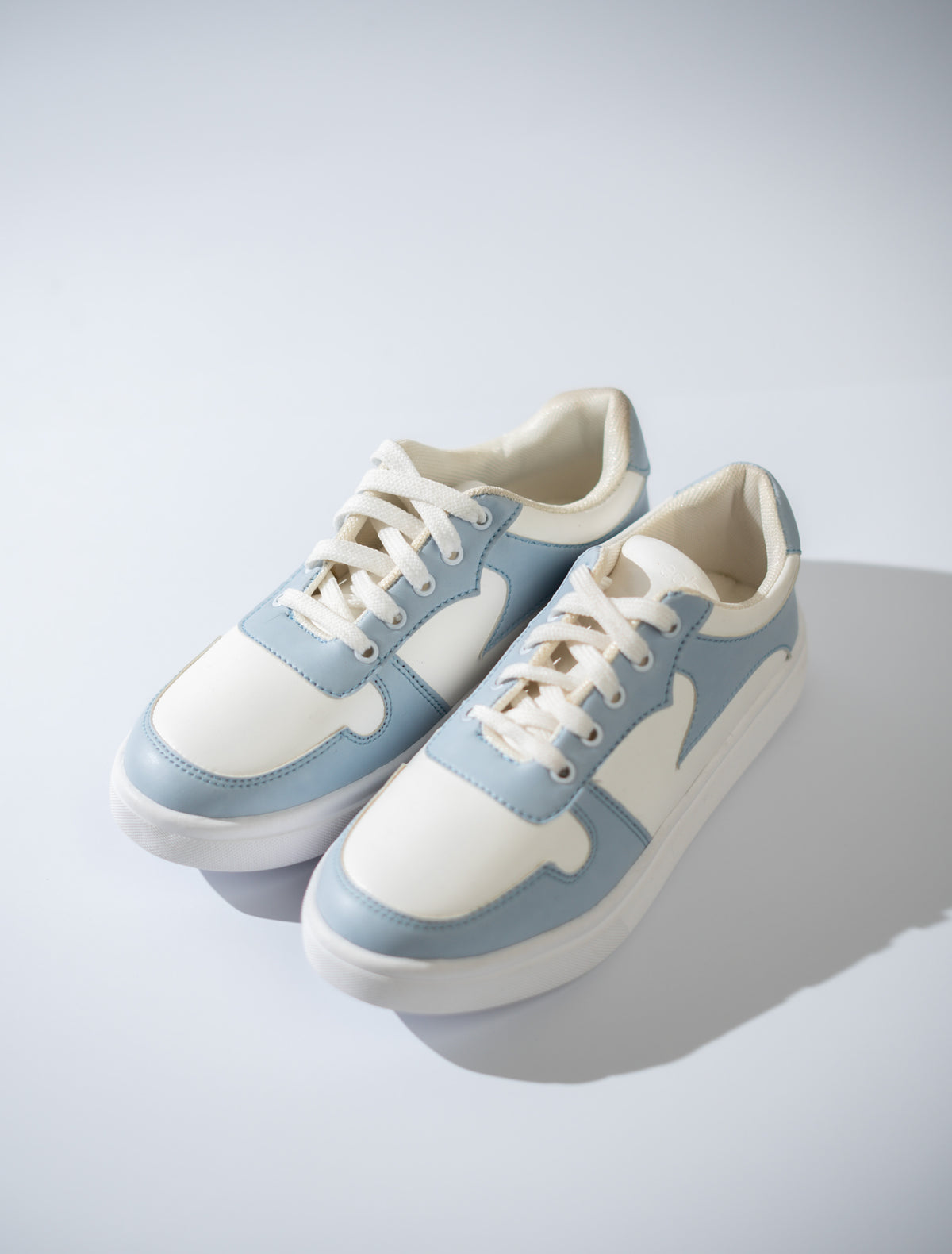 Pair of light blue and white sneakers on a gray background