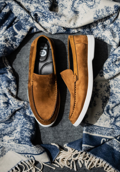 Pair of brown loafers on a textured blue and white fabric background
