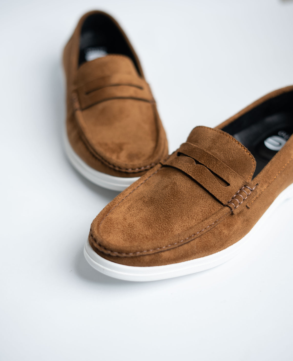 Brown suede loafers on a white background