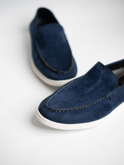 Pair of blue suede loafers on a light gray background