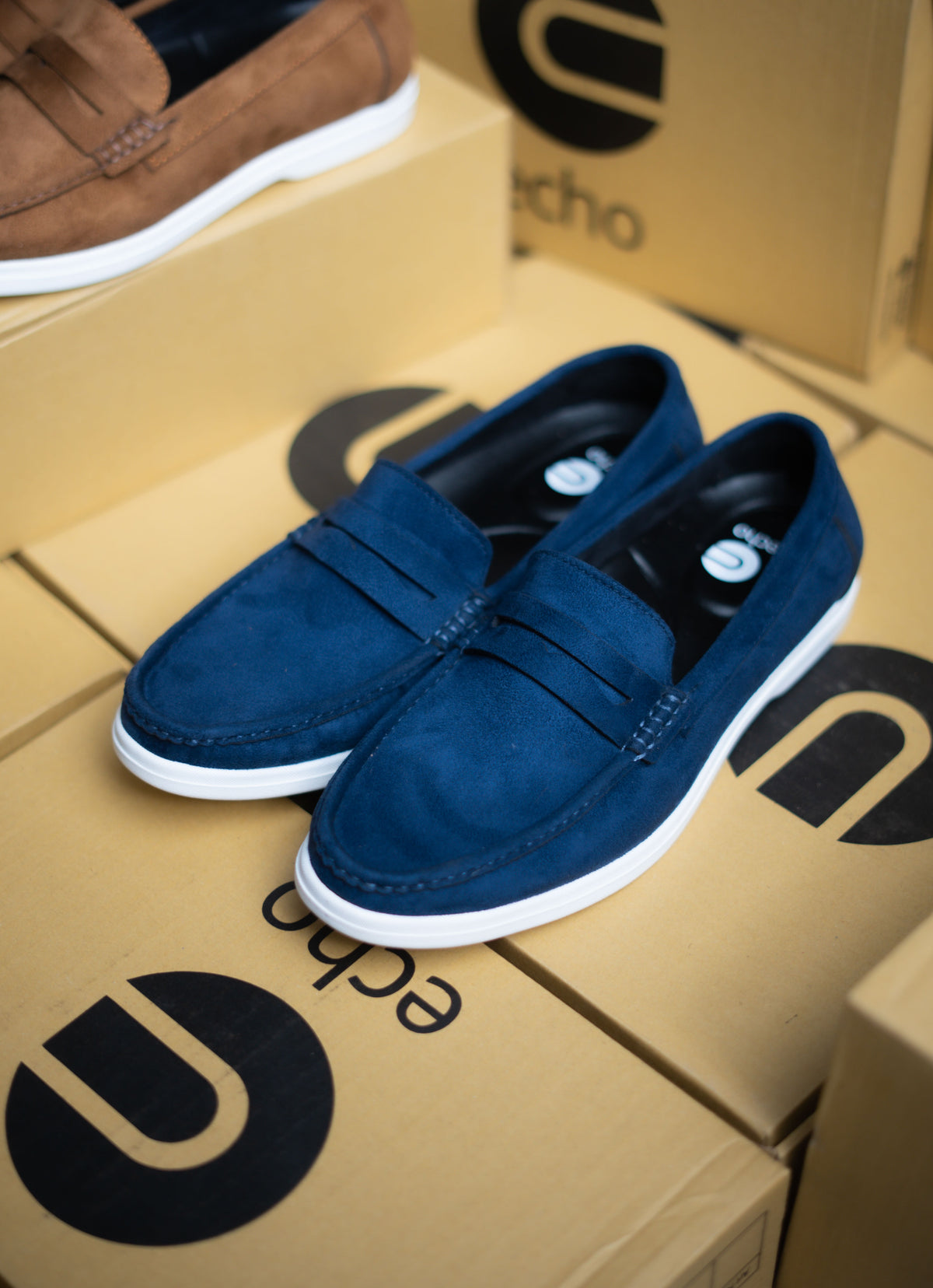 Blue loafers on a cardboard box with 'echo' branding