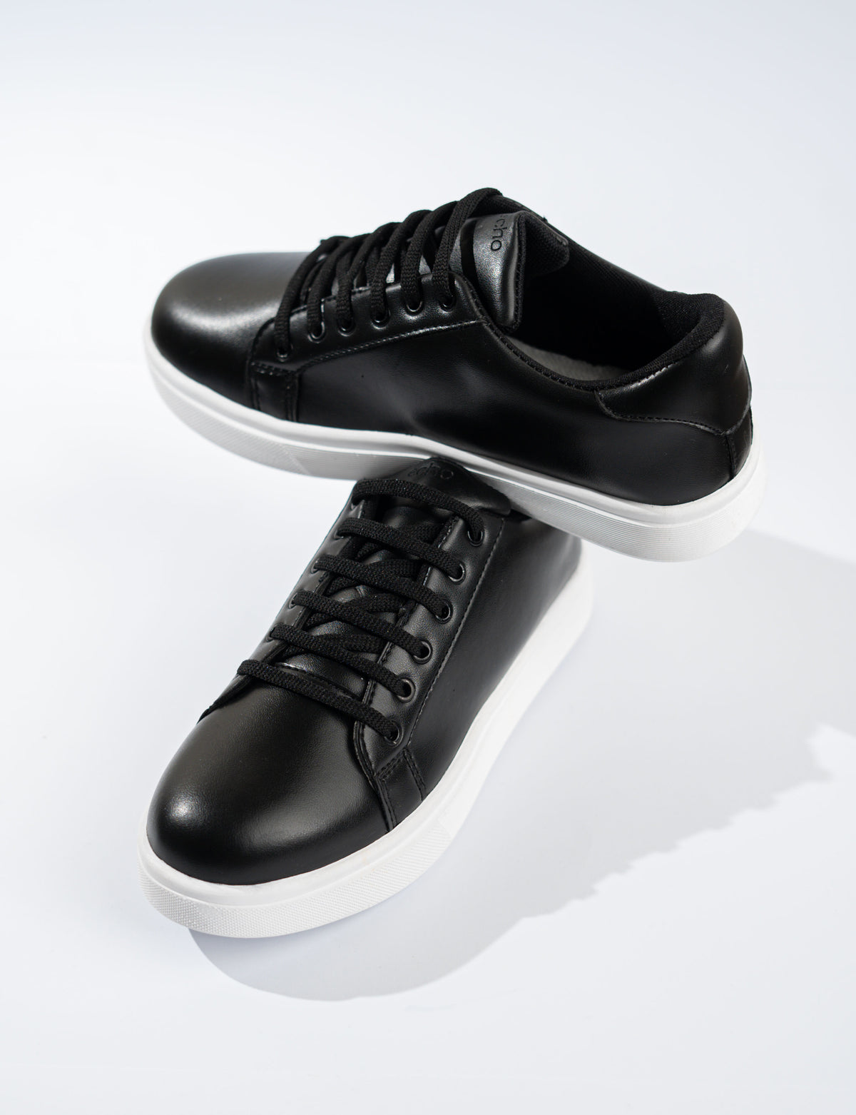 Black sneakers with white soles on a light gray background