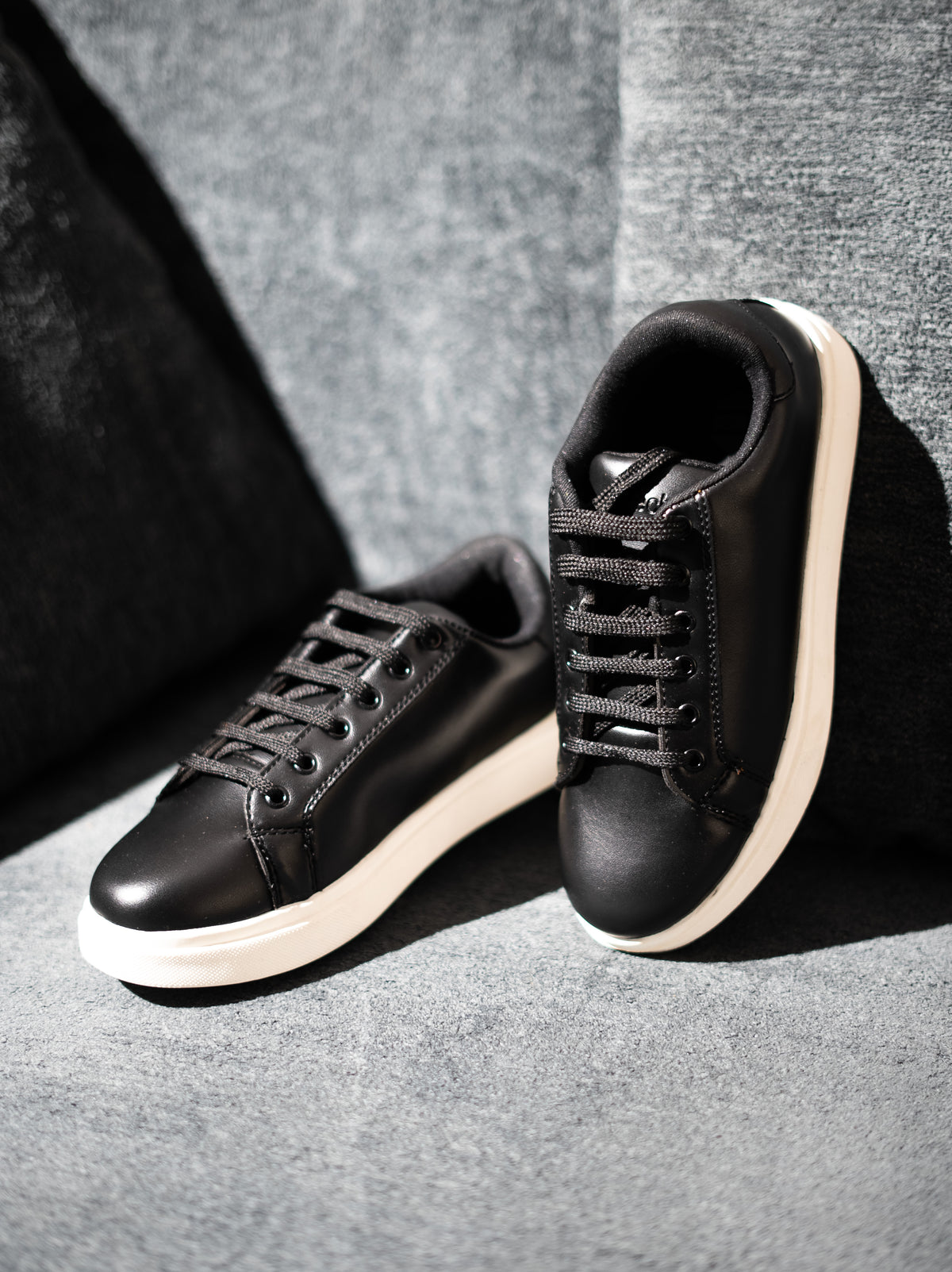 Black sneakers with white soles on a gray background