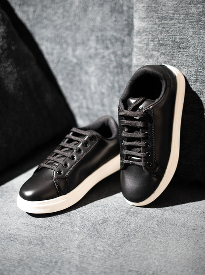 Black sneakers with white soles on a gray background