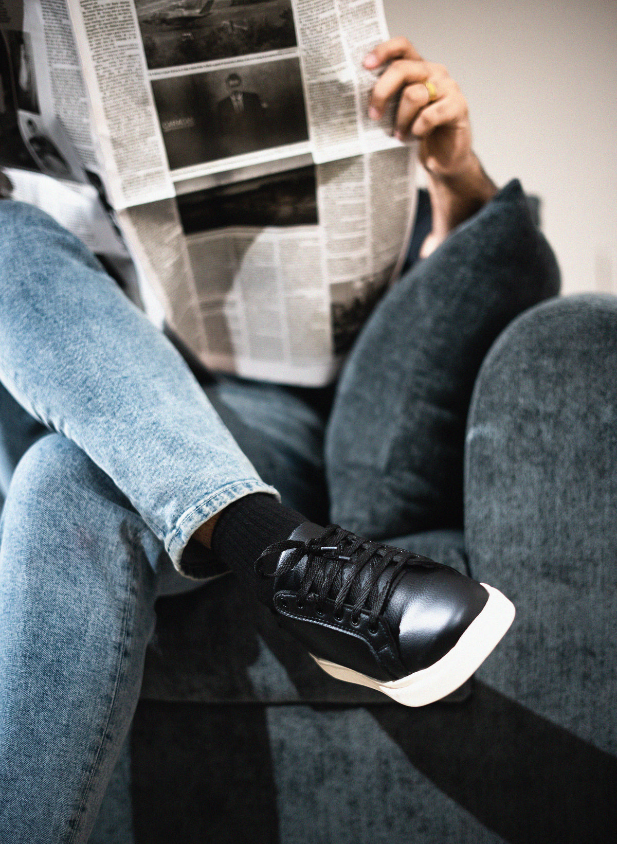 Person sitting on a couch reading a newspaper with a blurred background