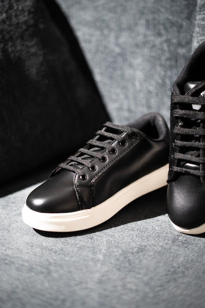 Black sneakers with white soles on a gray surface