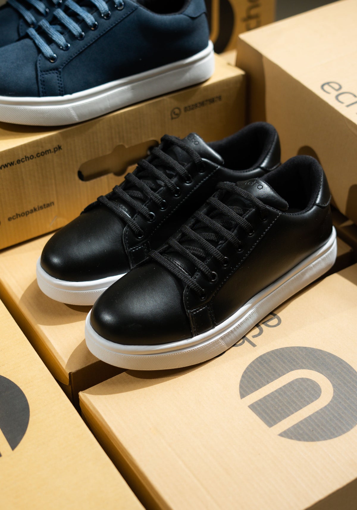 Black sneakers on a cardboard box with ECHO brand logo