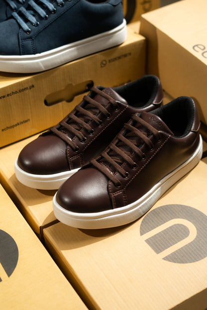 Brown sneakers on a cardboard box with a navy shoe in the background