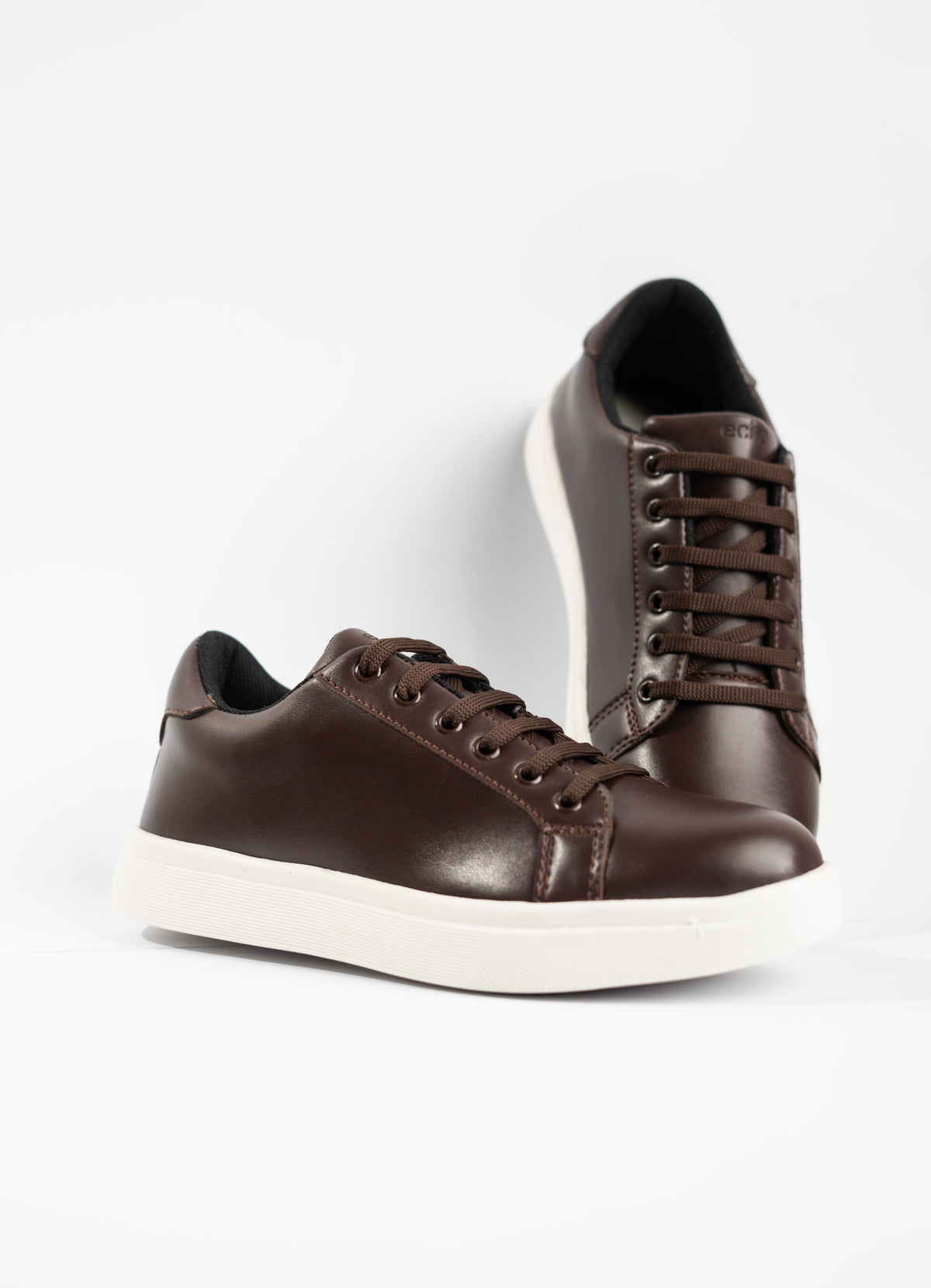 Pair of brown leather sneakers on a white background