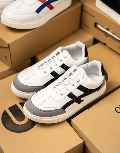 White sneakers with black and gray accents on a cardboard box
